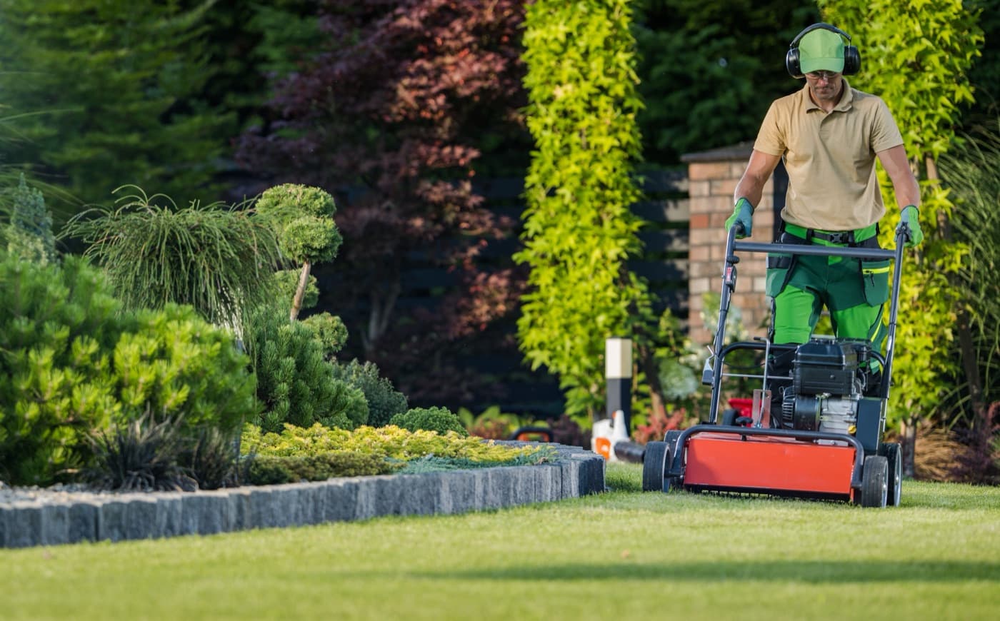Landscaper mowing a carefully planted residential garden