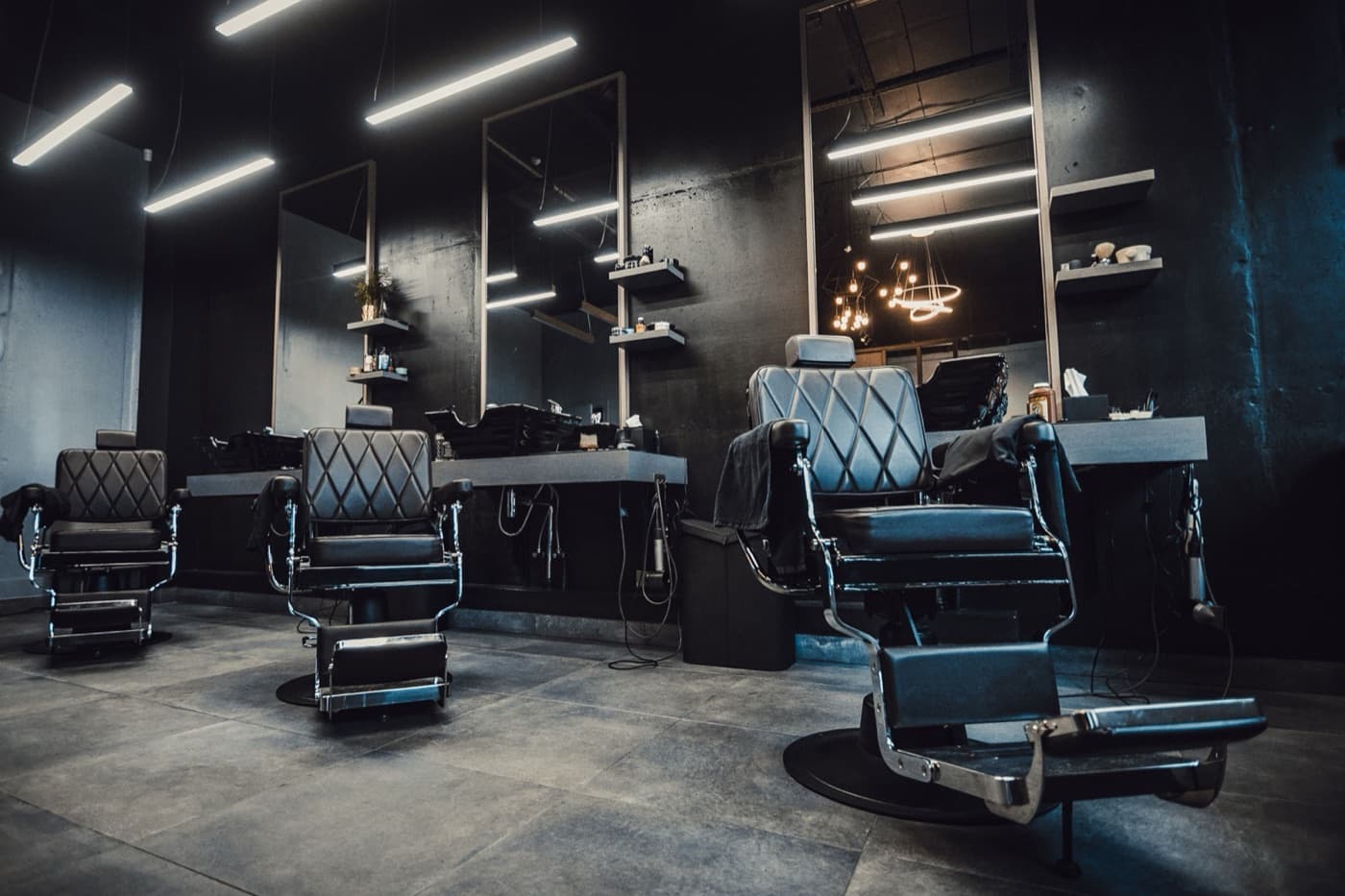 Dark modern barbershop with several empty barber chairs and mirrors