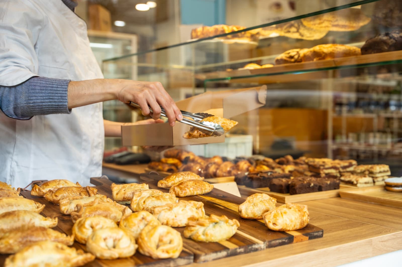 Baker packing fresh pastries at a bakery counter