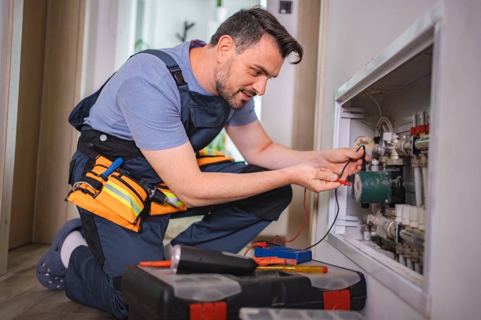 Plumber testing a home water-heating system with a multimeter